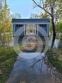 Flooded Huron River at old Greek Revival shelter at Island Park in Ann Arbor, Michigan