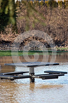 A flooded picnick bench in a park lawn