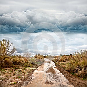 Flooded road in prairie and dramatic sky