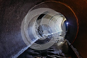 Flooded round sewer tunnel with water reflection