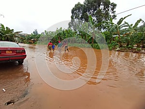 Flooded street in a district of dschang, users walk in water