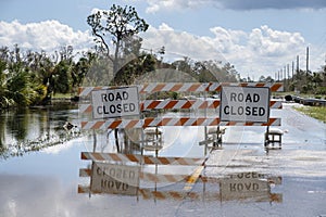 Flooded street in Florida after hurricane rainfall with road closed signs blocking driving of cars. Safety of