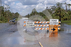 Flooded street in Florida after hurricane rainfall with road closed signs blocking driving of cars. Safety of
