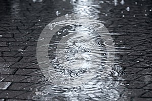 Flooded street sidewalk with rippled rain puddles