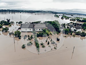 Flooded village on Ukraine. Natural disaster in Halych. Street with trees and houses in dirty river water photo