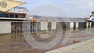 Flooding in city, high water level. Water spills along embankment, pier with boat. City Dnipro, Ukraine