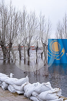 Flooding in the city of Kazakhstan in 2024.Sandbags and banner of Kazakhstan drowning in meltwater on background.