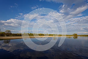 The flooding river in spring on the landscape with blue sky and water