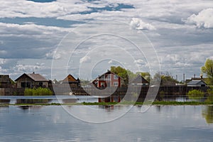 The flooding river in spring on the landscape with blue sky and water and the village