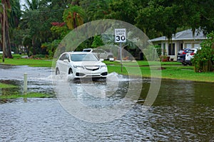 Flooding and storm surge in residential flooded neighborhood with car driving through deep water