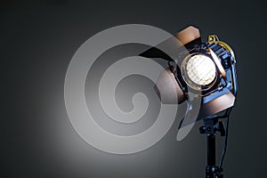 Floodlight with halogen lamp and Fresnel lens on a gray background. Lighting equipment for shooting