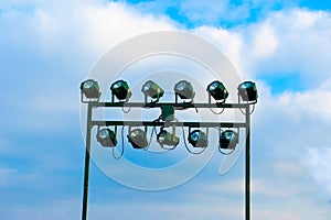 Floodlights in blue sky with clouds