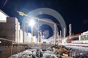 Floodlit tower crane on building construction site