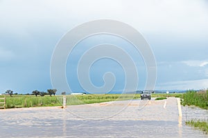 Floodwater across rural road with car and water depth measure