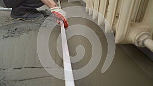 Floor cement work. Plasterer smoothing floor surface with screeder. Construction worker performs floor screed indoors