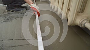 Floor cement work. Plasterer smoothing floor surface with screeder. Construction worker performs floor screed indoors photo