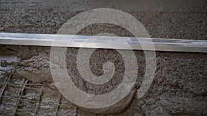 Floor cement work. Plasterer smoothing floor surface with screeder. Construction worker performs floor screed indoors photo