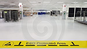 On a floor of the electronics manufacturing covered industrial linoleum pastes a yellow tape with a standard warning text: