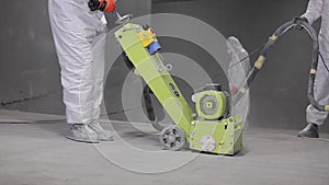 Floor grinding at a construction site. A builder works with an industrial grinder on a concrete floor. concrete floor