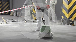 Floor grinding at a construction site. A builder works with an industrial grinder on a concrete floor. concrete floor