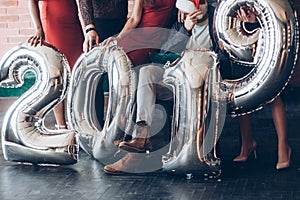 On the floor. Group of friends with inflatable numbers in hands celebrating new 2019 year