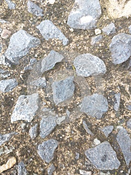 A floor that has several textured stones and various shapes with gray and black, this floor is resisting time