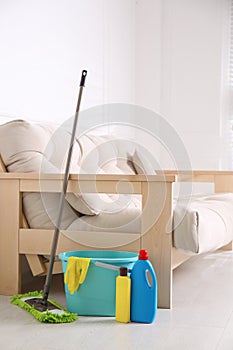Floor mop, cleaning detergents and bucket with gloves in room