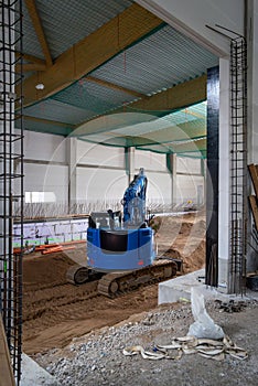 the floor of a newly built factory hall is excavated with an excavator
