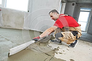Floor cement work. Plasterer smoothing floor surface with screeder photo