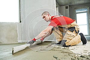 Floor cement work. Plasterer smoothing floor surface with screeder photo