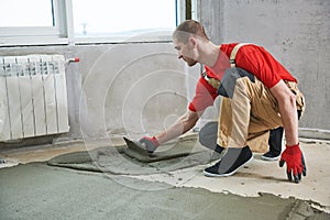 Floor cement work. Plasterer smoothing floor surface with screeder photo