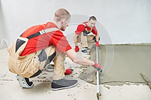 Floor cement work. Plasterer smoothing floor surface with screeder photo