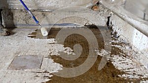 Floor priming process. A worker applies a primer to a concrete floor before laying a self-leveling floor. Primer for