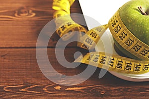 Floor scales, tape measure and green apple on a wood background top view. The concept of a healthy diet, body weight