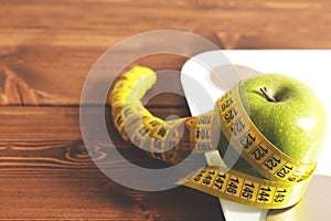 Floor scales, tape measure and green apple on a wood background top view. The concept of a healthy diet, body weight