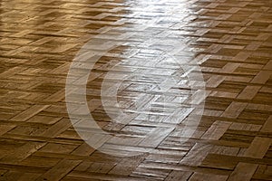A floor surface with light reflection. Closeup interior view of wood parquet floor. A pattern of bright clear brown rectangular