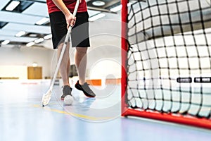 Floorball player training on court. Floor hockey concept. Man running with stick and ball in arena.