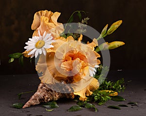 Floral arrangement with irises and daisies in a shell