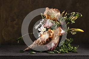 Floral arrangement with irises and daisies in a shell