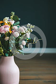 A floral arrangement in a pink vase set against a dark backdrop
