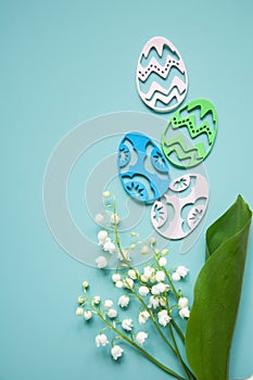 Floral blue background with fresh flowers. Spring greeting card for Easter. A bouquet of lily of the valley and a gift, eggs