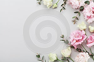 Floral border of beautiful flowers and green eucalyptus leaves on gray table top view. Flat lay composition.