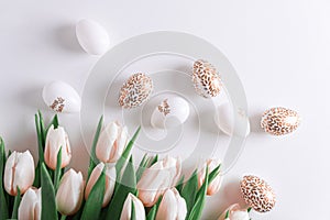 Floral border from bouquet of pink tulips, Easter eggs and toys on white background. Easter celebration concept. Copy space. Top