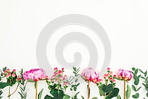 Floral border frame of pink peonies, hypericum and eucalyptus on white background. Flat lay, top view