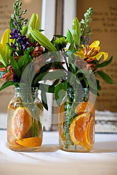 Floral bouquets in jars with oranges