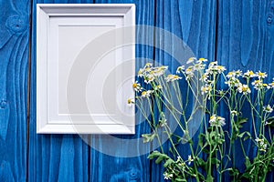 Floral composition with camomile and frame on blue wooden background flat lay mockup