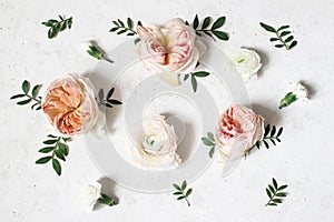 Floral composition with pink English roses, ranunculus and green leaves on white concrete table background. Flower