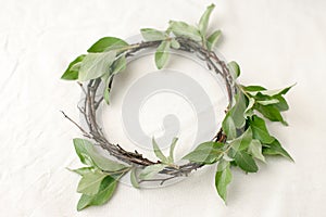 Floral composition. Wreath made of roools, leaves, and flowers on tissue white background. Rustic style of home decor, flat lay,