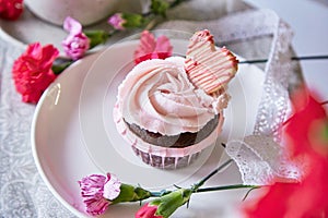 Floral cupcake among flowers decoration. Escapism concept of dreamy french desserts. Spring food background