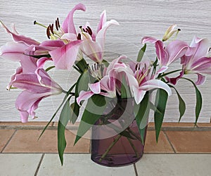 Floral display including Flashpoint pink and white Oriental Trumpet Lily in a transparent vase